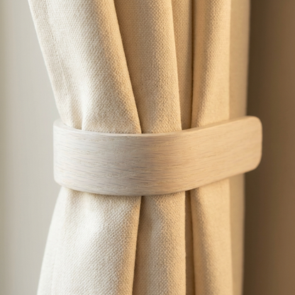 Close-up of beige curtains with a tieback against a neutral background
