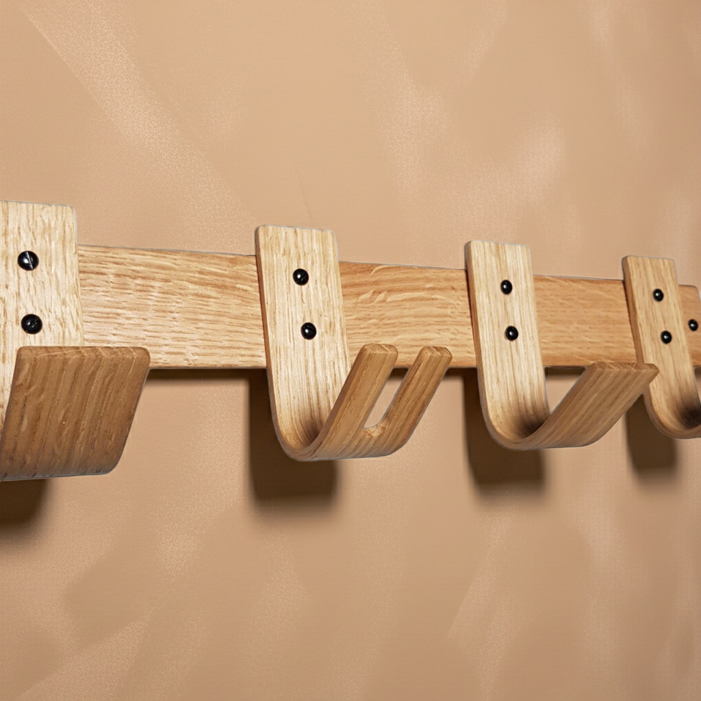 Wooden wall-mounted coat rack with four hooks on a beige background